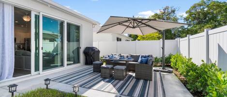 A backyard with a patio area, outdoor furniture, and a grill.