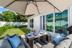Eine Terrasse im Freien mit einem Esstisch, umgeben von Korbmöbeln und blauen Kissen.