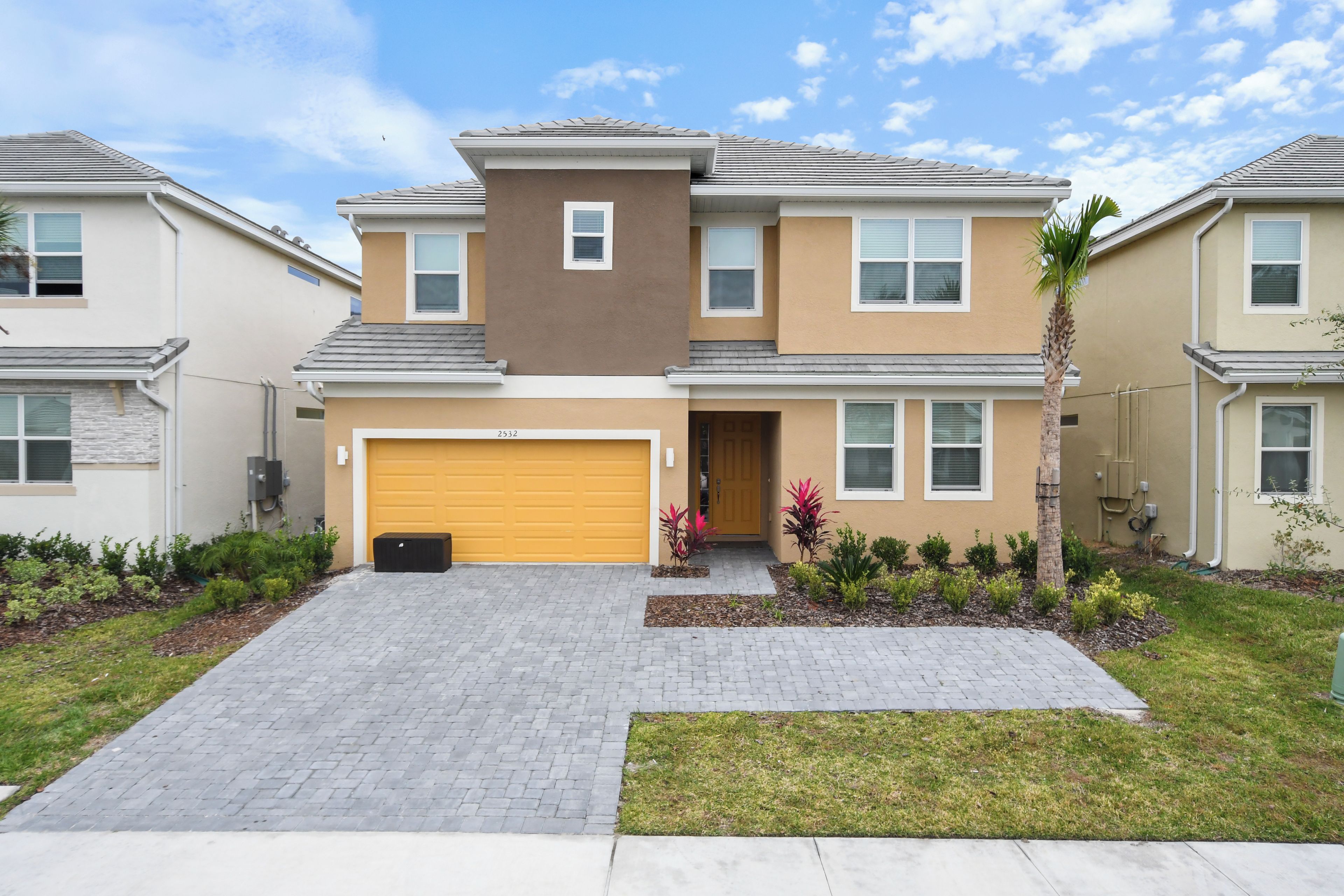 A two-story residential building with a garage, a driveway, and a well-maintained garden.