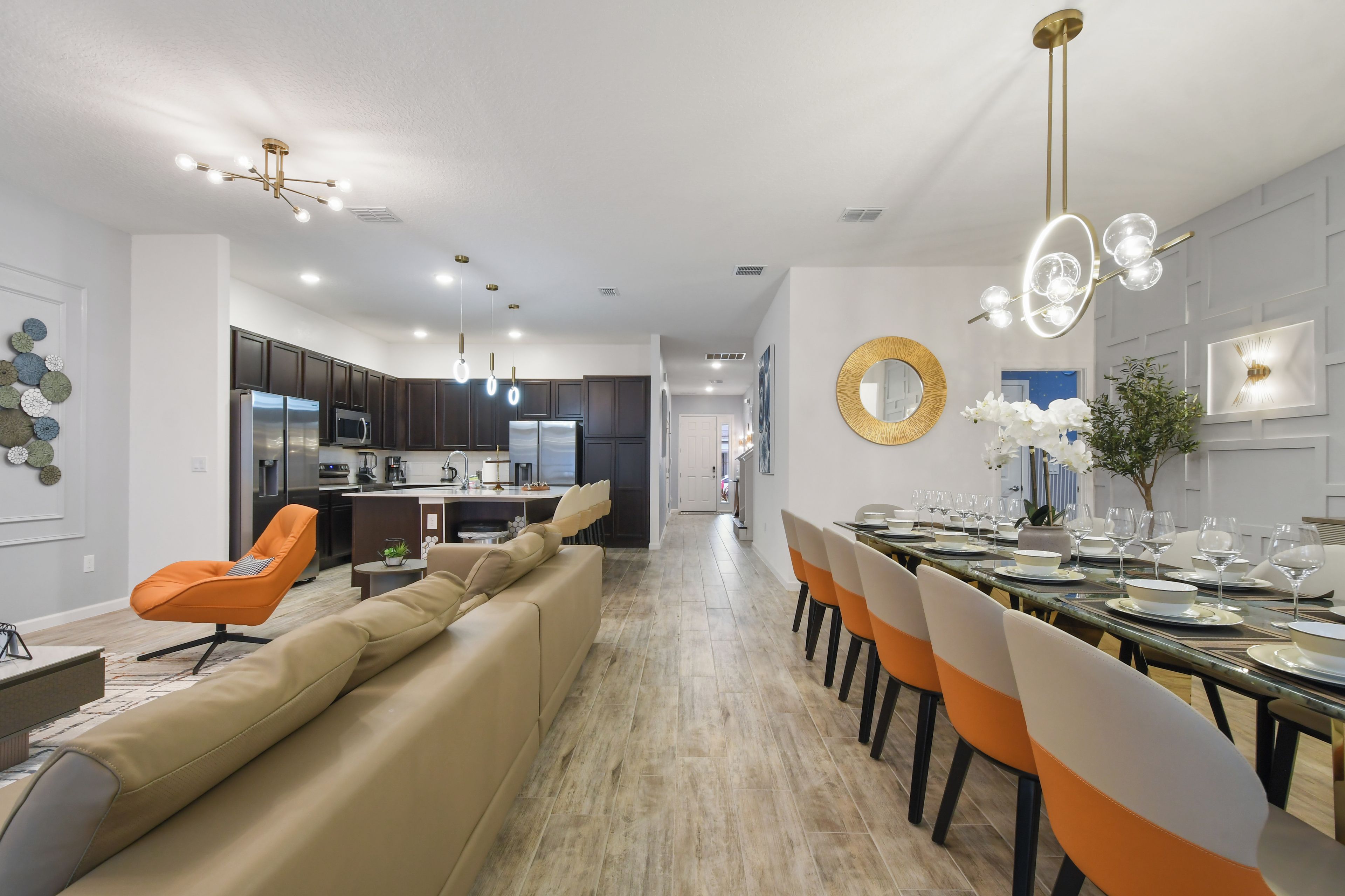 A modern kitchen with dark cabinets, a central island, and a dining area with a long table set for six.