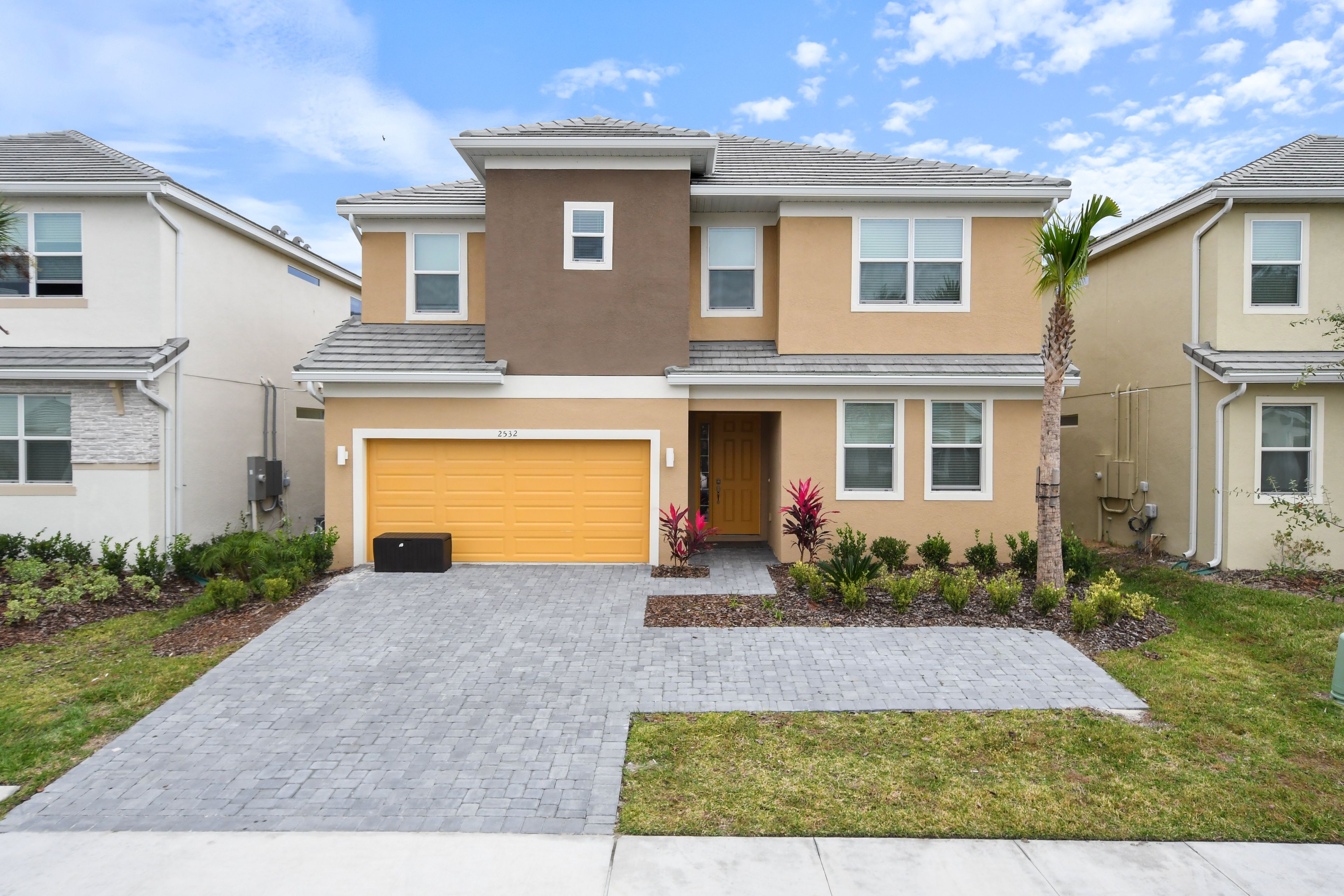 A two-story residential building with a garage, a driveway, and a well-maintained lawn.