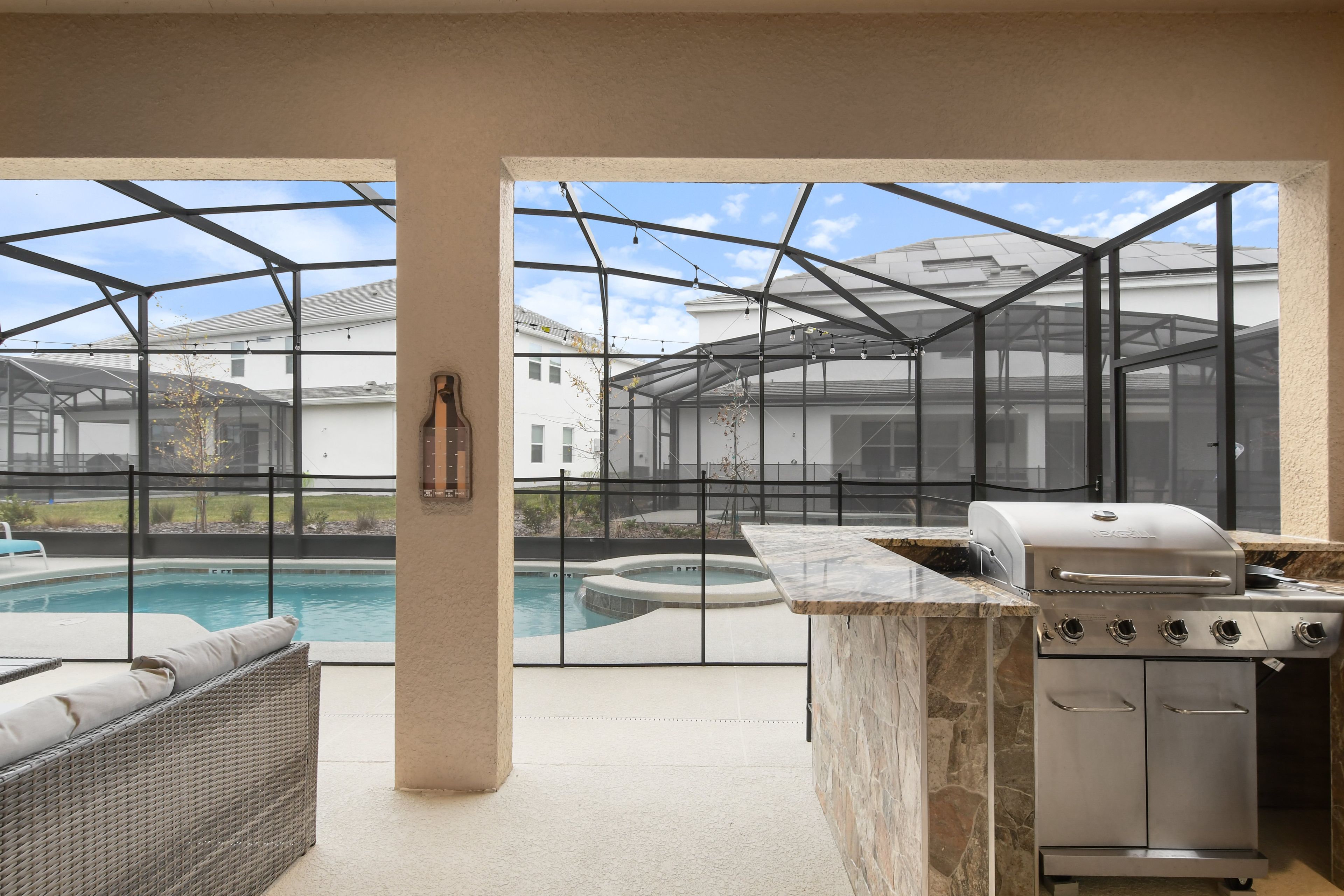 An outdoor kitchen area with a grill, a pool, and a seating area.