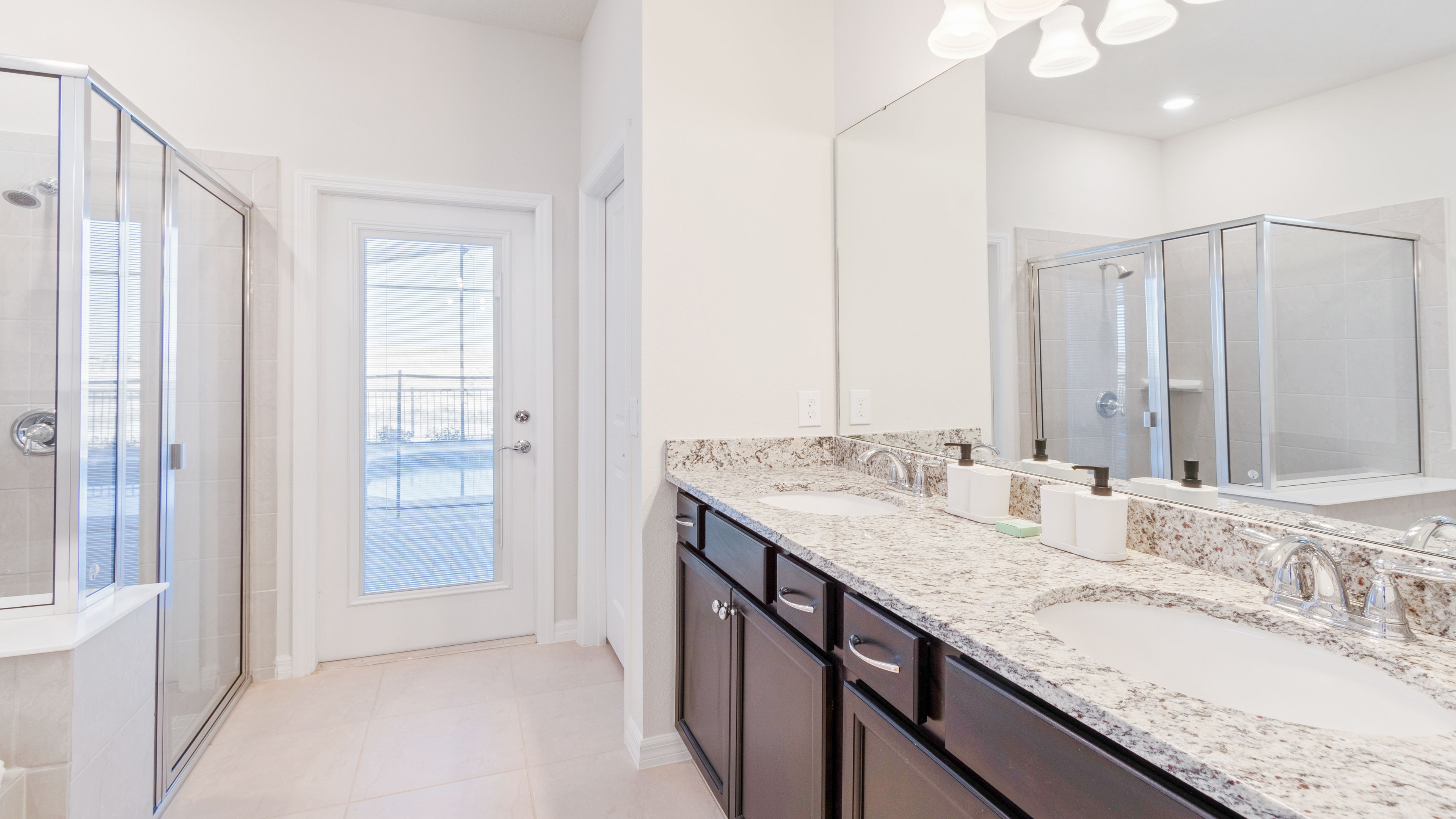 A modern bathroom with a glass shower enclosure, a double sink vanity, and a large mirror.