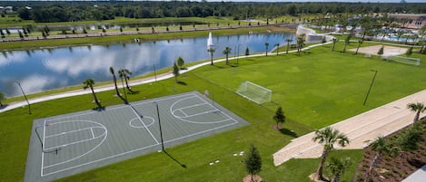 Ein Basketballplatz im Freien mit einem Wasserspiegel und Bäumen im Hintergrund.