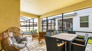 A covered patio area with wicker furniture, a table, and chairs. - Epic Game Loft & Space-themed Theater Experience (Kissimmee)