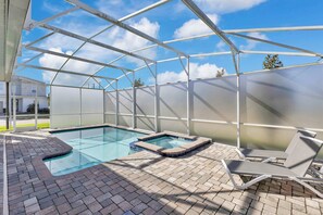A covered outdoor swimming pool with a glass roof, a hot tub, and lounge chairs. - Resort Villa w/ Game Room & Disney Murals (Davenport)