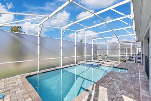 A covered swimming pool with a clear blue sky above, surrounded by a white metal frame and a tiled deck. - Resort Villa w/ Game Room & Disney Murals (Davenport)