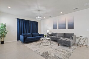 A living room with two sofas, a coffee table, a chandelier, and a potted plant. - 6BR Villa w/ Private Pool Near Disney (Davenport)