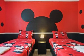 A room with two beds, each with red bedding featuring cartoon characters, a nightstand with a lamp, and a large wall mural of a cartoon character's head. - 6BR Villa w/ Private Pool Near Disney (Davenport)