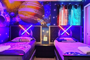 A room with two beds, a nightstand with a lamp, and a wall mural of space and planets. - 6BR Villa w/ Private Pool Near Disney (Davenport)