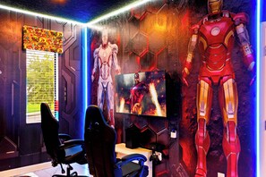 A gaming room with two gaming chairs, a TV, and two large Iron Man statues. - Luxury Storey Lake Villa With Starry Theater (Kissimmee)