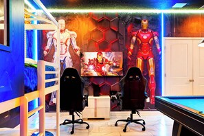 A gaming room with bunk beds, gaming chairs, a pool table, and Iron Man posters. - Luxury Storey Lake Villa With Starry Theater (Kissimmee)