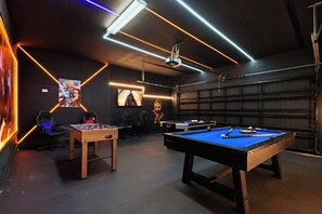 A room with a pool table, foosball table, and two gaming chairs. - Windsor Island Retreat 7BR Pool Home (Davenport)