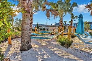 A sandy beach area with hammocks and lounge chairs, palm trees, and a clear sky. - Windsor Island Retreat 7BR Pool Home (Davenport)