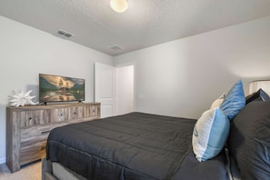 Ein Schlafzimmer mit Bett, Schminktisch, Fernseher und einer Tür.