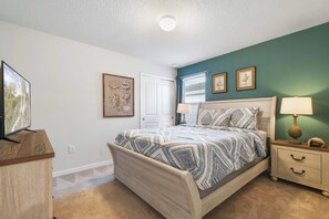 Une chambre à coucher comprenant un lit, des tables de chevet, une commode et un téléviseur.