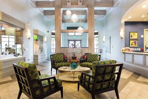 A lobby with a high ceiling, a central seating area with patterned chairs, and artwork on the walls. - Championsgate Townhome w/ Private Pool (Davenport)
