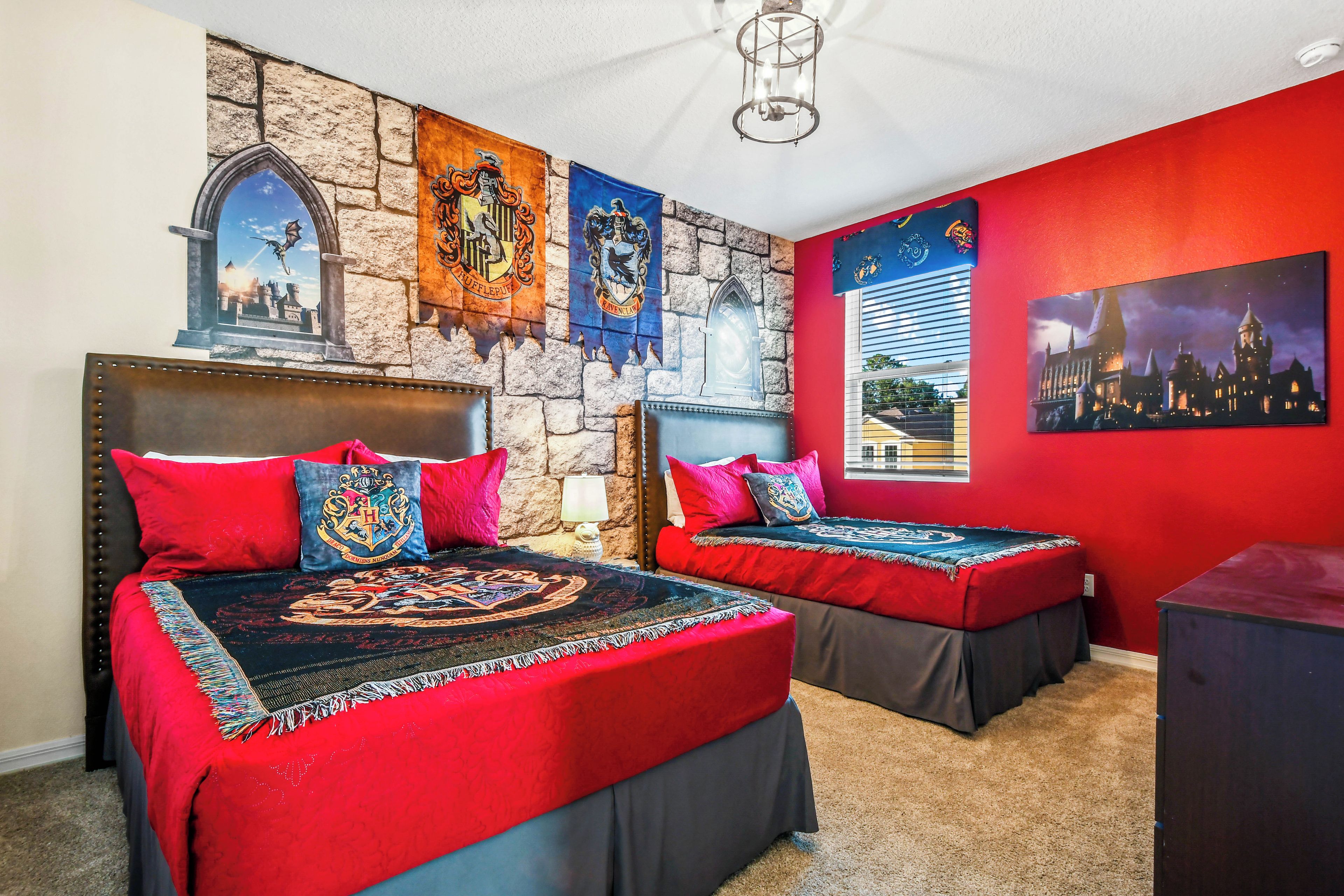 A bedroom with two beds, red walls, and a stone wall.
