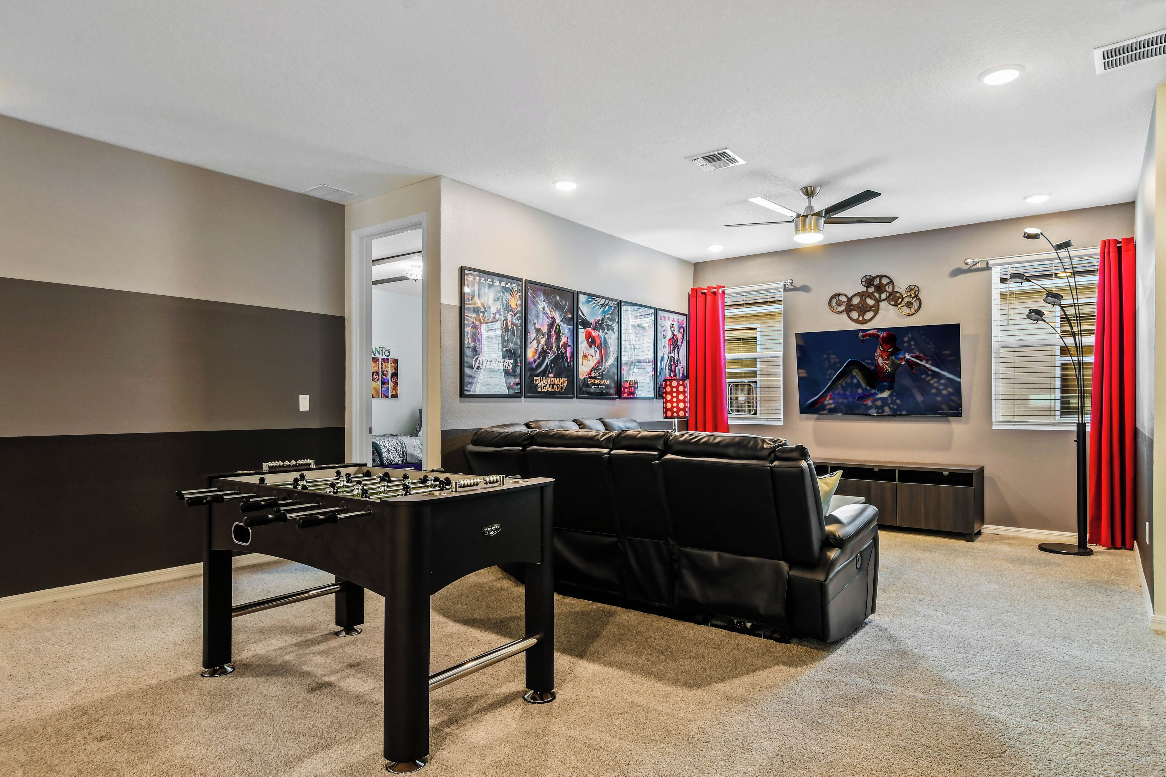 A room with a foosball table, a large flat-screen TV, and a sofa.