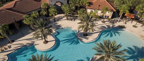 Un resort con una gran piscina central, palmeras y un edificio de techo rojo.