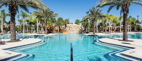 Una piscina amplia y cristalina rodeada de palmeras y sillas de descanso.