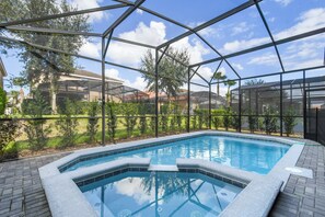 A swimming pool with a glass enclosure, surrounded by greenery and residential buildings. - Solterra Villa Private Pool, Games & Themes (Davenport)