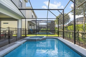 A swimming pool with a glass enclosure, a patio area with chairs, and a view of a house. - Solterra Villa Private Pool, Games & Themes (Davenport)