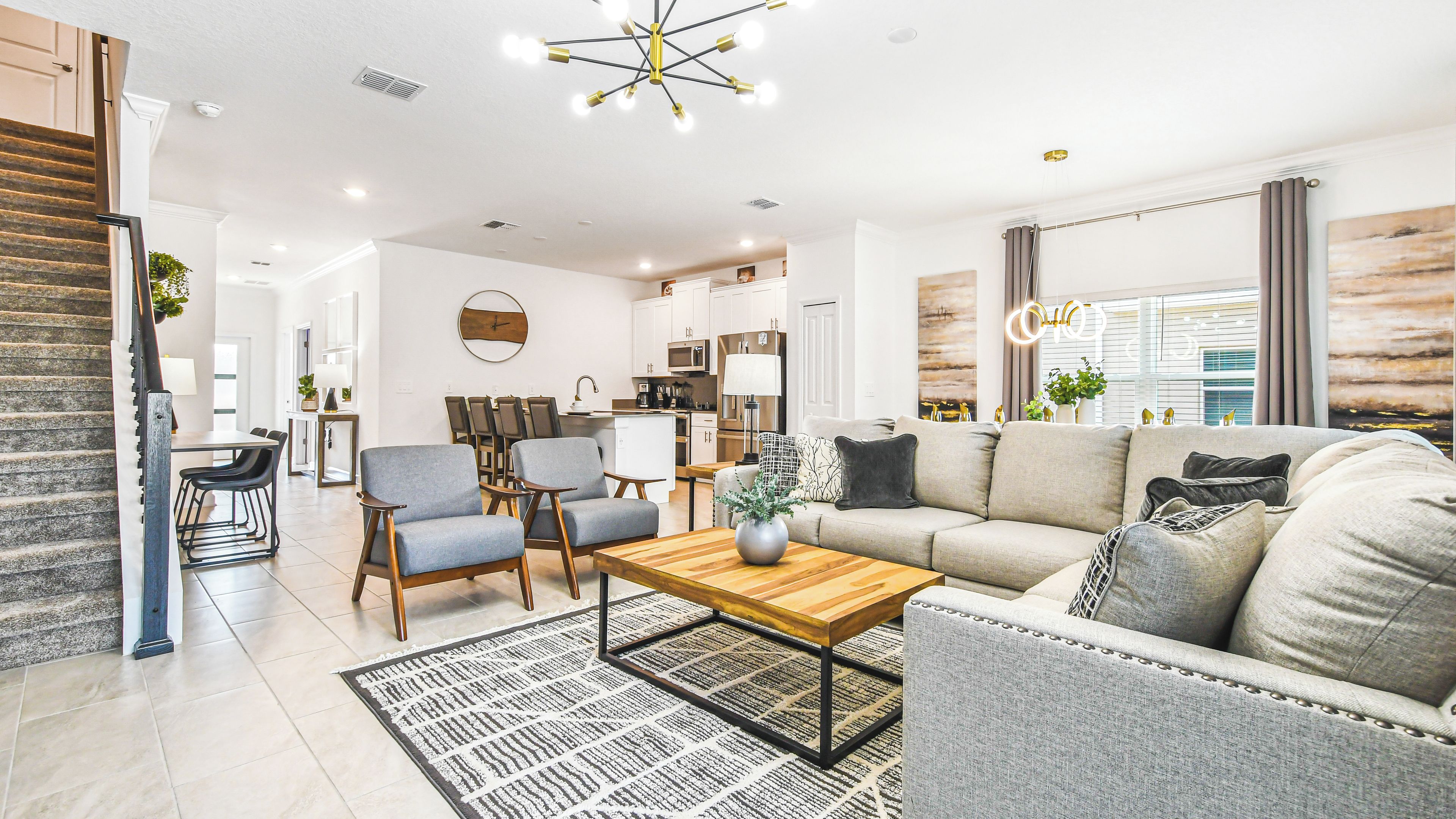 A modern living room with a sofa, chairs, a coffee table, and a dining area with chairs and a table.