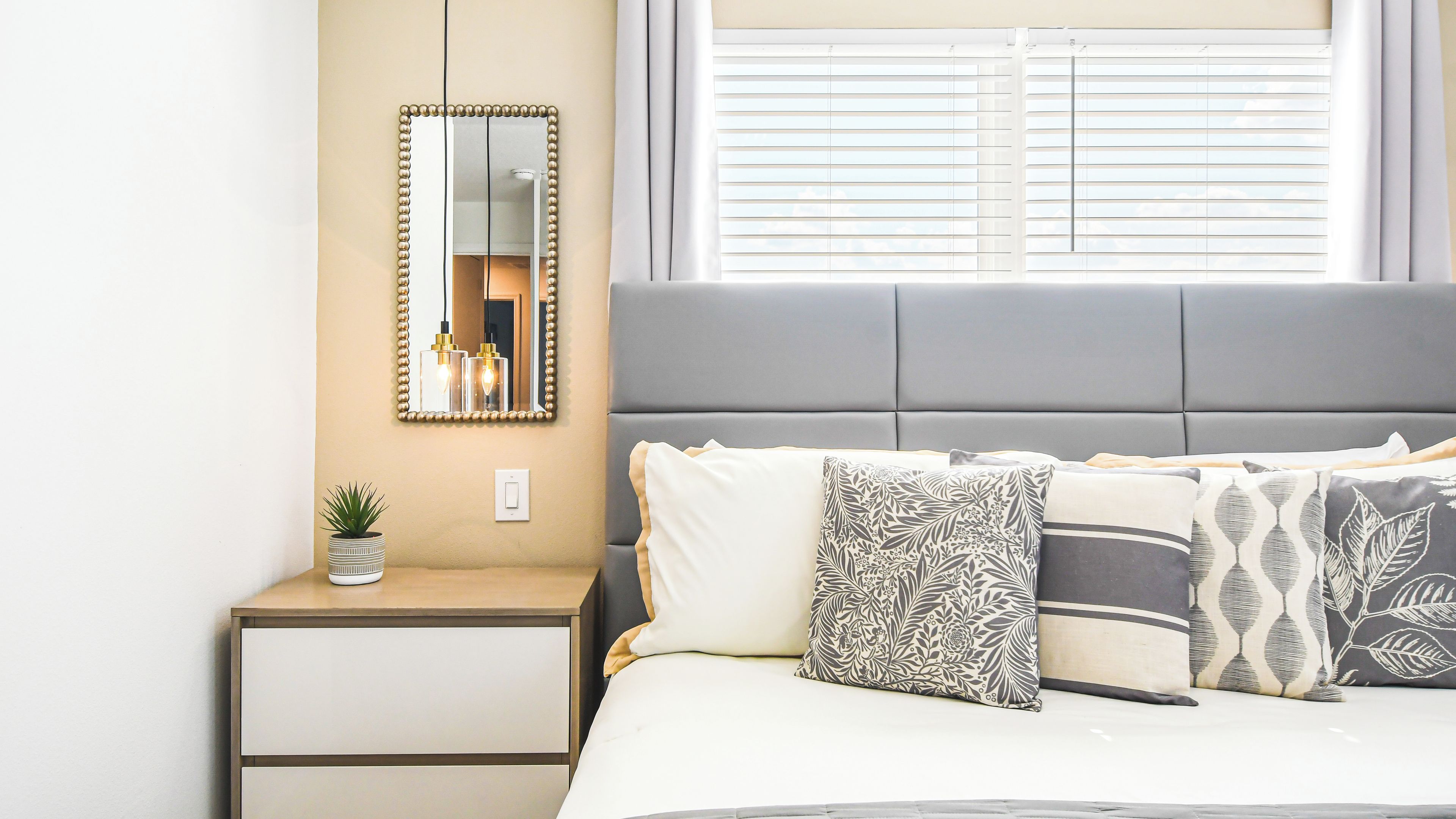 Een slaapkamer met een bed, nachtkastje en een spiegel.