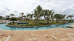 Piscina com deck ladrilhado, cercada por palmeiras e espreguiçadeiras.