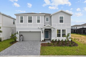 A two-story residential building with a garage, a front door, and a small front yard with plants. - Minion Themedprivate Pool Game Room & Green Views (Davenport)