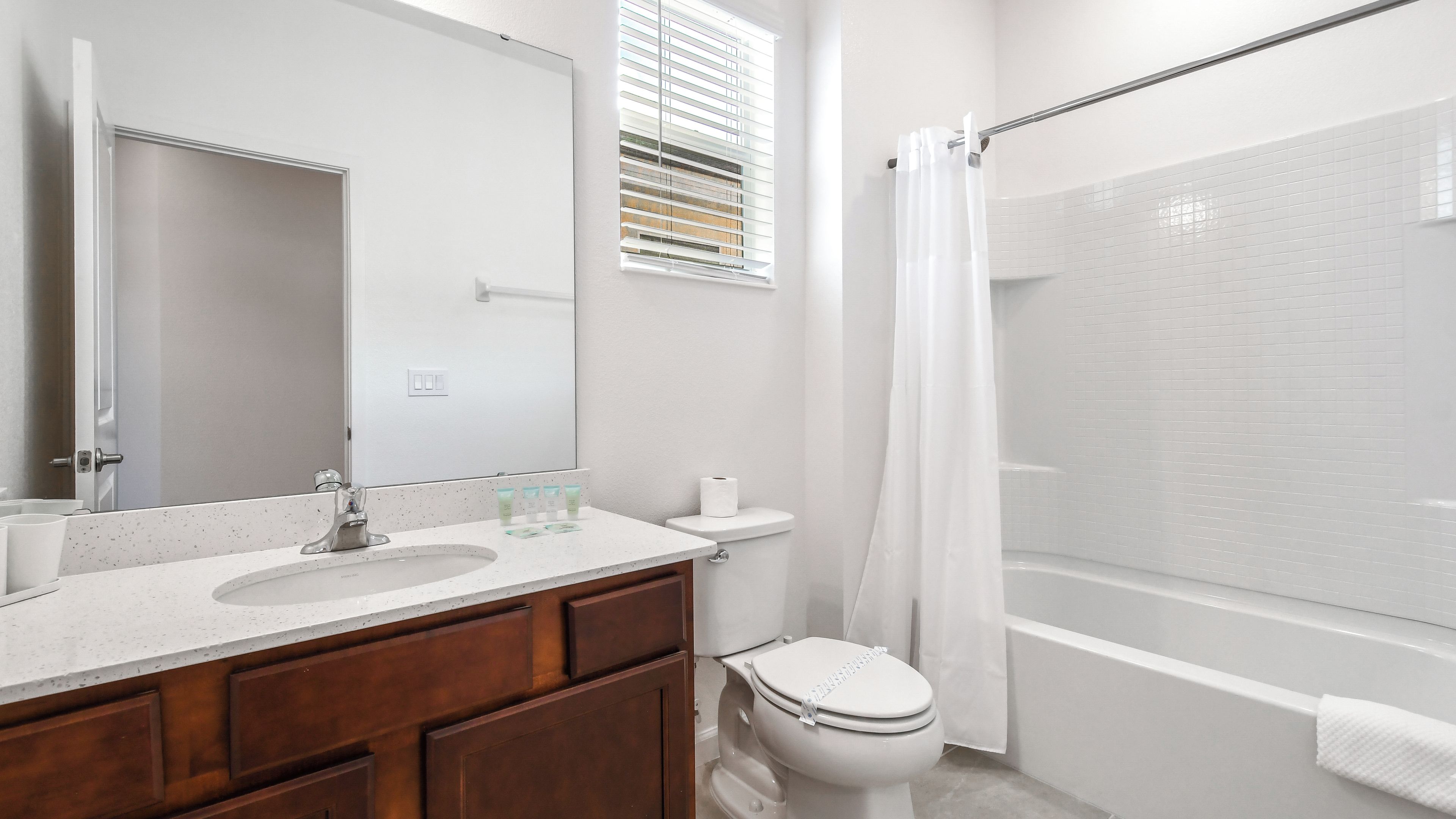 Baño con lavamanos, espejo, inodoro y ducha.