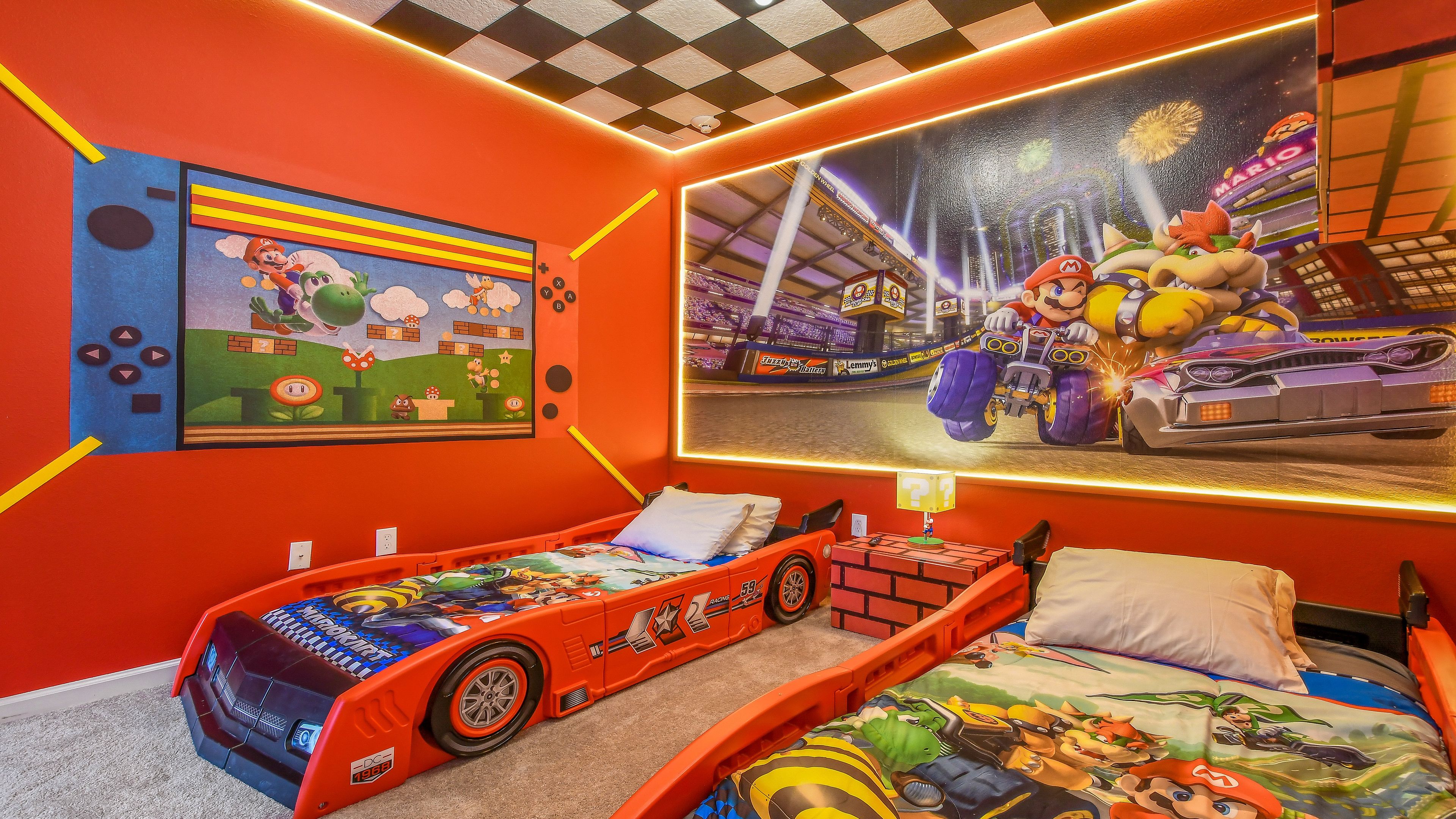 Een kinderkamer met een Mario-bed, een raceauto-bed en een muurschildering van Mario Kart.