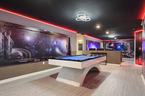 A pool table in a room with a large space-themed mural on the wall, ambient lighting, and a modern ceiling design. - Best Rate 10br/frozen/space BR & Marvel Gameroom (Davenport)