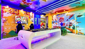 A vibrant room with a foosball table, a large Super Mario mural, and gaming chairs. - Mermaid & Snow White-themed Escape Near Disney (Davenport)