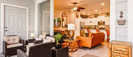 A spacious living area with wicker furniture, a sofa, and a dining table.