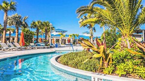 A swimming pool with lounge chairs and palm trees, surrounded by buildings with blue roofs. - Vibrant Villa With Tropical Mural & Fun Bunk Beds (Davenport)