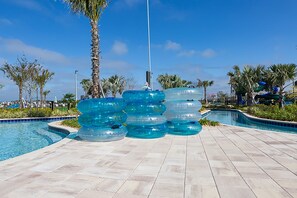 Área de piscina com vários boias e palmeiras.