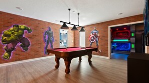 A room with a pool table, brick walls, and superhero murals. - Star Wars & Encanto Bunk Rooms + Pool @ Storeylake (Kissimmee)