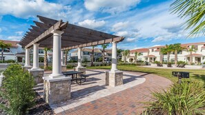 A covered outdoor area with stone columns, a brick patio, and a view of residential buildings. - Star Wars & Encanto Bunk Rooms + Pool @ Storeylake (Kissimmee)