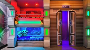 A futuristic room with a bunk bed, a small bed with a starry night view, and an exit door with a keypad. - Star Wars & Encanto Bunk Rooms + Pool @ Storeylake (Kissimmee)