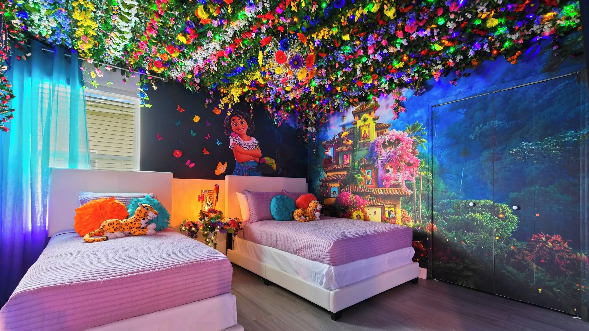 Une chambre avec deux lits, une fresque murale et une grande fenêtre.