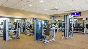 A gym with various exercise machines, mirrors, and a television screen. - 8BR Family Getaway Private Pool (Kissimmee)