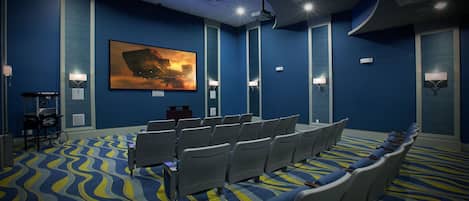 Une salle de conférence avec des rangées de chaises, un grand tableau accroché au mur et un projecteur au plafond.