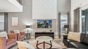 A modern living room with a flat-screen TV, leather sofas, a marble coffee table, and a patterned wall. - Hogwarts to Arendelle: Themed Magic Near Disney (Kissimmee)
