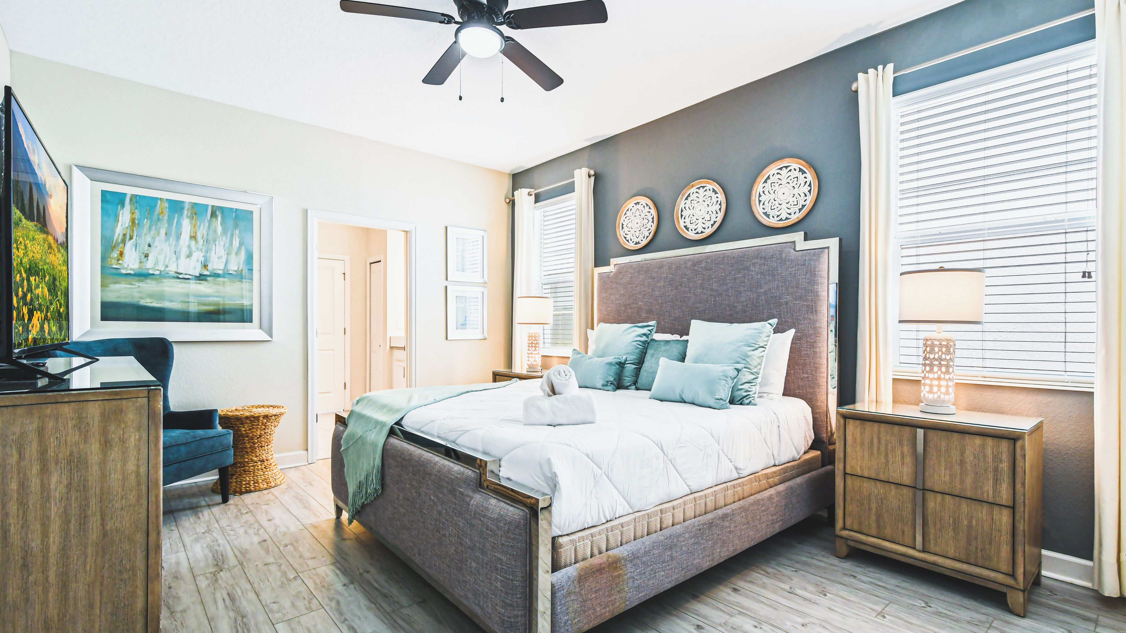 A bedroom with a bed, bedside tables, a ceiling fan, and a window with blinds.