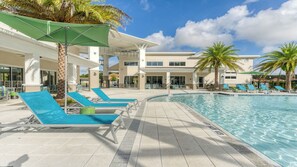 A pool area with lounge chairs and umbrellas, a clear sky, and palm trees. - Private Pool Home w/ Minions & Superhero Themes (Kissimmee)