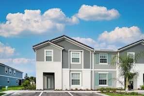 A modern multi-story residential building with a flat roof, large windows, and a well-maintained lawn. - 5BR @ Solterra Resort w Pool & Disney-themed Rooms (Davenport)
