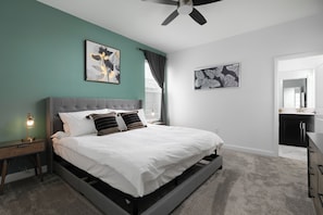 Ein Schlafzimmer mit einem Bett, einem Nachttisch, einem Deckenventilator und Kunstwerken an den Wänden.