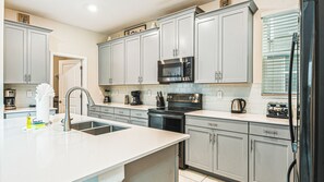 A modern kitchen with grey cabinets, stainless steel appliances, and a white countertop. - Harry Potter~frozen Room 5BR w Game Room, Disney! (Kissimmee)